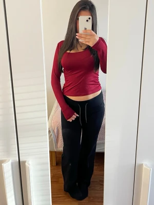 Mörkröd långärmad topp - Snygg mörkröd långärmad topp med tight passform och rundad halsringning. Perfekt att matcha med jeans eller mjukisbyxor för en chill look. Materialet känns mjukt och stretchigt, vilket gör den riktigt bekväm att bära.