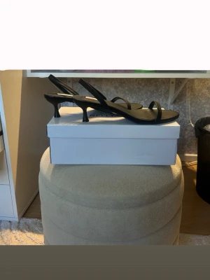 Svarta pumps med smal klack från Nelly - Stilrena svarta pumps från Nelly med smal rem över tårna och öppen häl. Endast testade, så i nyskick. 