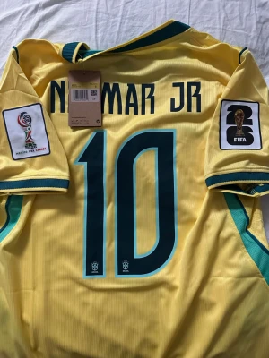 Brasilien VM-tröja, neymar 10 - Brasiliens VM hemmatröja från Nike med Neymar JR och nummer 10 på ryggen. Tröjan är helt ny och har vm loggorna på axeln. Storlek S.