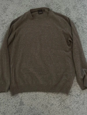 Brun stickad tröja från Oscar Jacobson - Mjuk och stilren brun stickad tröja från Oscar Jacobson. Tröjan har rund halsringning, långa ärmar och ribbade muddar vid ärmslut och nederkant. Extremt klädsam och går bra med en skjorta undertill! Storlek XL men passar mig ok som är 184cm. 