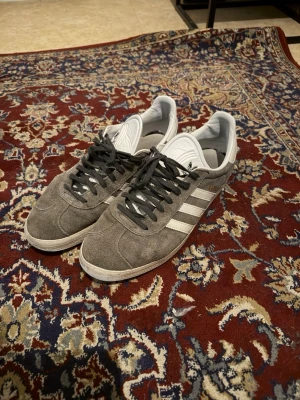 Grå Adidas Gazelle sneakers - Säljer ett par grå Adidas Gazelle skor. Bra skick. Dm för info och fler bilder. LÅDA FÅS MED. Pris diskuteras