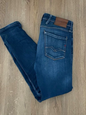 Replay anbass - Snygga mörkblå jeans från Replay med klassisk femficksmodell och coola slitningar framtill. Jeansen har en skinnpatch bak i midjan och kontrastsömmar på bakfickorna. Tillverkade i mjuk denim med stretch för extra komfort.