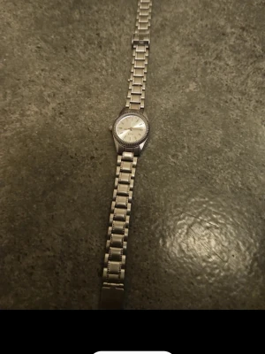Silverfärgad klocka - Stilren klocka med silverfärgat armband och rund urtavla. Klockan har en klassisk design med metallarmband och en ljus urtavla med minimalistiska markeringar. Perfekt för dig som gillar tidlös stil och enkelhet.