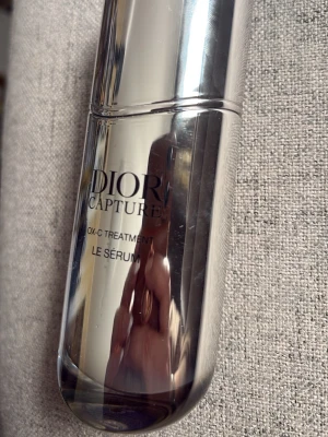 Dior Capture OX-C Treatment Serum - Exklusivt serum från Dior Capture-serien, OX-C Treatment Le Sérum. Flaskan är elegant och silvrig med pumpfunktion, perfekt för dig som vill boosta hudens lyster och fukt. Passar dig som gillar lyxiga hudvårdsprodukter och vill ha en snygg detalj på badrumshyllan.
