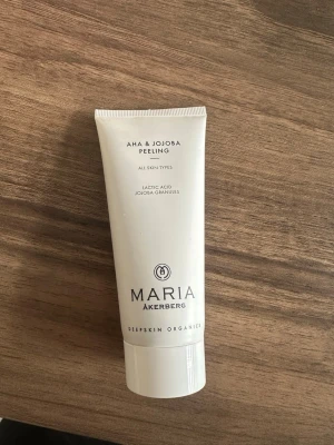 AHA & Jojoba Peeling Maria Åkerberg - AHA & Jojoba Peeling från Maria Åkerberg är en vit tub med peeling för alla hudtyper. Innehåller mjölksyra och jojobakorn, perfekt för att exfoliera huden och ge en fräsch känsla. Tuben är stilren och har en organisk känsla.