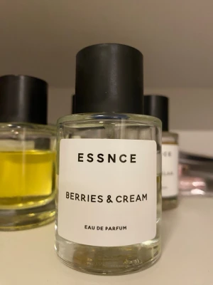 Essnce Berries & Cream Eau de Parfum - En parfym från Essnce med doften Berries & Cream. Flaskan är cylindrisk i klart glas med svart matt kork och vit etikett med svart text. Parfymen har en ljusgul nyans och känns modern och stilren. Perfekt för dig som gillar fruktiga och krämiga dofter.