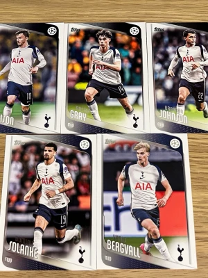 Topps Tottenham Hotspur samlarkort - Fem samlarkort från Topps med Tottenham Hotspur-spelare. Korten har färgfoton på spelarna i matchställ, klubbens logga och Champions League-märke. Baksidan innehåller spelarinformation och statistik. Perfekt för dig som gillar fotboll och samlar på sportkort.