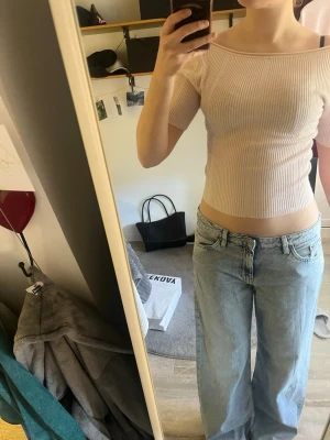 Ljusrosa ribbad crop top - Trendig ljusrosa ribbad crop top med korta ärmar och öppen rygg. Toppen är figurnära och har en stretchig känsla som framhäver siluetten. Perfekt att matcha med höga jeans för en avslappnad look.