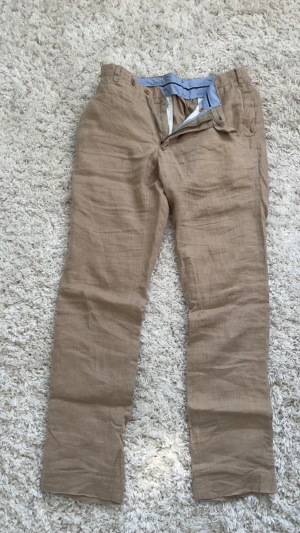 Ralph Lauren linnebyxor  - Snygga beige linnebyxor med raka ben och klassisk passform. Byxorna har blå innerkant i midjan, bälteshällor och fickor både fram och bak med knappstängning. Perfekta för en avslappnad och stilren look. Hör av dig om du har frågor🙌