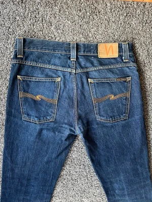 Grim Tim dry  - As feta nudie jeans i dry modell vilket innebär att de kommer utveckla sjuka fades ju mer du använder de! Jeansen är i väldigt bra skick!