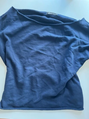 Mörkblå off-shoulder topp från Gina Tricot - En enkel mörkblå topp från Gina Tricot med rund halsringning och avslappnad passform. Tillverkad i mjukt bomullsliknande material som känns skönt mot huden. Perfekt att styla med jeans eller kjol för en clean look.