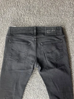 Svarta jeans från Jacob Cohen - Snygga svarta jeans från Jacob Cohen med raka ben och klassisk femficksmodell. Jeansen har en stilren look med diskreta sömmar och svart patch bak i midjan. Perfekta för dig som gillar en clean och modern stil.
