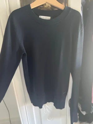 Mörkblå stickad tröja Holly & Whyte - En stilren mörkblå stickad tröja från Holly & Whyte by Lindex. Tröjan har rund halsringning, långa ärmar och ribbade muddar vid hals, ärmslut och nederkant. Skriv om fler blinde eller diskutera priset 