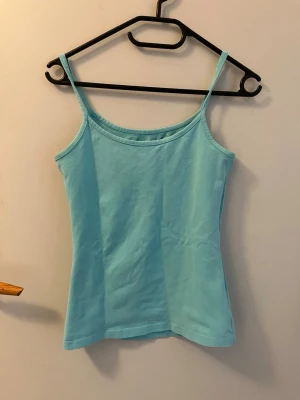 Ljusblå linnetopp från H&M L.O.G.G. - Säljer en enkel och fräsch ljusblå linnetopp från H&M:s L.O.G.G.-kollektion. Toppen har smala axelband och är tillverkad i mjuk bomull, perfekt för varma dagar eller som lager under andra plagg. Fräsch och känns ny