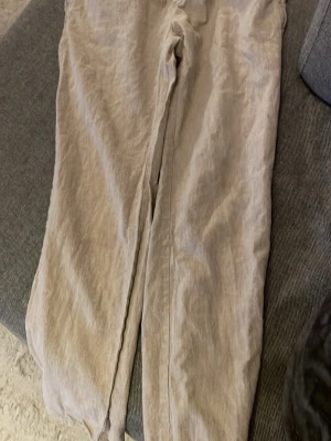 Beige linnebyxor med resårmidja - Säljer ett par beige linnebyxor från C i storlek M. Byxorna har resår i midjan och är gjorda i en skön blandning av linne och bomull. Perfekta för en avslappnad och stilren look.