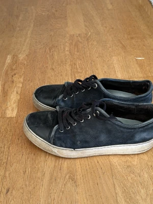 Svarta låga sneakers i mocka - Snygga svarta sneakers med ovandel i mocka och tåparti i slätt skinn. Skorna har svarta skosnören, metallfärgade öljetter och vit sula. Perfekta för en avslappnad streetstil och passar till det mesta i garderoben. Pris kan absolut diskuteras, storlek 41 men sitter som 42-42,5, tar byten