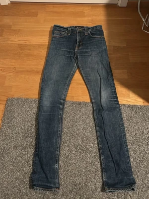 Blå jeans från Nudie Jeans - Säljer ett par blå jeans från Nudie Jeans med klassisk femficksdesign .
