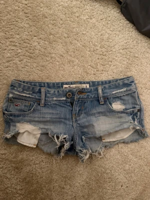 Ljusblå lågmidjade slitna jeansshorts Hollister - Säljer ett par ljusblå jeansshorts från Hollister med låg midja. Shortsen har slitna detaljer, fransig kant och klassisk femficksdesign. Perfekta för sommaren💕 Midjemåttet är 37cm. Tar emot prisförslag