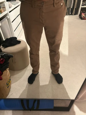 Replay Bruna chinos med stretch - Snygga bruna chinos med slim fit och klassisk design. Byxorna har framfickor, bälteshällor och två bakfickor med passpoal. Perfekta för en clean och stilren look. Materialet känns mjukt och följsamt,  bomull med  stretch.