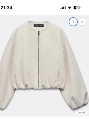 Vit/beige cardiganjacka från Zara - Trendig vit/beige cardiganjacka från Zara med rund halsringning och dragkedja framtill. Jackan har ballongärmar och två fickor på sidorna. Tillverkad i ett mjukt, fleece-liknande material som ger en avslappnad och modern look.