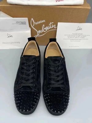 Christian louboutin - Snygga svarta sneakers från Christian Louboutin i mocka med svarta nitar på tån. Klassisk låg modell med svarta skosnören och diskret logga på hälen. Perfekta för dig som vill sticka ut med en edgy och exklusiv stil.