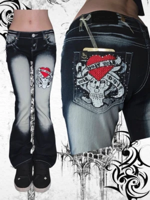 Blå jeans med dödskalle och hjärta (blue queen) - Säljer ett par blå-svarta jeans från Blue Queen med coolt dödskalle- och hjärta-brodyr på benet och bakfickan. Jeansen har utsvängda ben, slitna detaljer och kontrastsömmar. Materialet är denim med tvättad effekt och detaljer i vitt och rött. 36cm över midjan