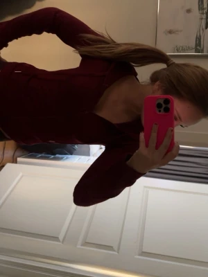 Vinröd ziptröja med hög krage - Snygg vinröd ziptröja med hög krage och långa ärmar. Tröjan har en figurnära passform och dragkedja framtill. Perfekt för en avslappnad och sportig look.