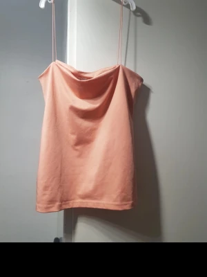 Ljusrosa linnetopp med tunna band - Snygg ljusrosa linnetopp med tunna axelband och avslappnad passform. Perfekt för varma dagar och enkel att styla med jeans eller kjol. Mjuk och skön känsla i materialet. Storlek:S