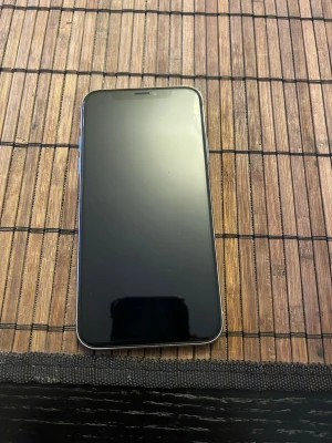 Silverfärgad iPhone X med glasbaksida - Säljer en stilren iPhone X i silver med glasbaksida och rundade kanter. Telefonen har en stor skärm utan hemknapp och dubbla kameror på baksidan. Klassisk Apple-design med logga och metallram. Perfekt för dig som gillar snygg och modern teknik. Kosmetiskt skick: TOPP skick. Batterihälsa 80%. Funkar perfekt som extra telefon. 