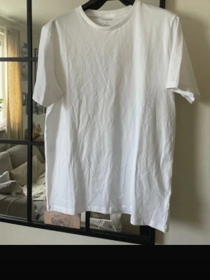 Vit t-shirt från Lindbergh Essentials - Klassisk vit t-shirt från Lindbergh Essentials i storlek L. T-shirten har rund halsringning och korta ärmar. Tillverkad i mjuk bomull för en skön och enkel stil som passar till allt. Helt ny