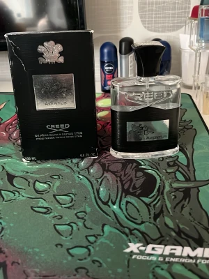 Creed Aventus Eau de Parfum 120ml - Creed Aventus Eau de Parfum i 120 ml flaska. Flaskan är genomskinlig med svart band och silveretikett med logga och text. Kommer med original svart kartong med silverdetaljer. En exklusiv och ikonisk doft för dig som vill sticka ut.