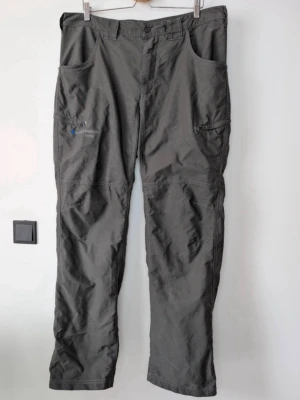 Grå frilufsbyxa från Klättermusen - Säljer ett par grå cargobyxor från Klättermusen, modell Fenrir. Byxorna har flera stora fickor, bälteshällor och en rak passform. Tillverkade i slitstarkt material som passar perfekt för äventyr och vardag. Snygg och funktionell design med diskret logga på benet.