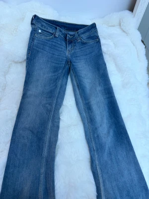 Blå bootcut jeans från Cheap Monday - Säljer ett par klassiska blå bootcut jeans från Cheap Monday. Jeansen har fem fickor, normal midja och en snygg tvättad look. Tillverkade i denim med en vit Cheap Monday-logga bak i linningen. Perfekta för en avslappnad och trendig stil.