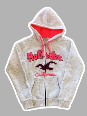 Vit Hollister zip up hoodie - Snygg vit hoodie från Hollister. Insidan av luvan är rosa och resten av insidan har ett mjukt vitt material (inte säker på vad för material). Där framme står det Hollister och California och där finns även deras fågel logo. Perfekt för båda killar och tjejer, den har både en y2k/stockholmsstils look och en lite mer Grisch/archive stil. Skriv för mer info eller bilder, pris är diskuterbart! 🩷❣️