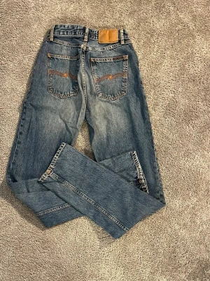 Blå nudie jeans - Säljer ett par snygga blå Nudie Jeans i bra skick. De är väl omhändertagna och har mycket kvar att ge.  Obs: dragkedjan är trasig, men det är en enkel och billig fix hos skräddare eller om du kan laga själv. I övrigt är jeansen i fint skick utan större slitage.  Perfekta om du vill göra ett kap! ✨