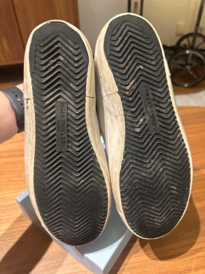 Philippe Model vita sneakers - Snygga vita sneakers från Philippe Model med klassisk låg siluett. Skorna har ovandel i läder och mocka, vita snören och diskret logga på plösen. Yttersulan är i svart gummi med tydligt mönster för bra grepp. Perfekta för en clean och stilren look.