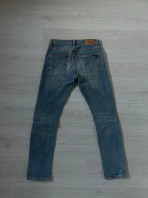 Nudie Jean lean dean  - Authentic Nudie Jeans Lean Dean model in light wash denim, size 28/30, purchased in Gothenburg. These jeans offer a slim fit, showing some wear with fading and subtle distressing adding to their unique character. Please refer to photos for specific details, as these are pre-owned. Feel free to ask any questions!