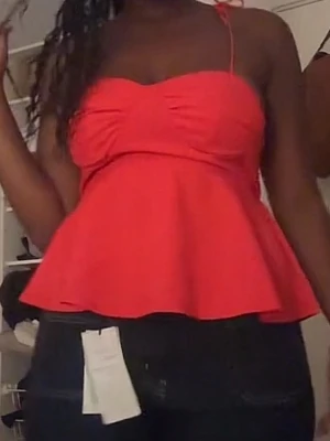 Röd topp med knytband - Trendig röd topp med peplumvolang och smala axelband som knyts på axlarna. Snygg sweetheart-urringning och figurnära passform upptill. Perfekt för dig som vill ha en färgstark och feminin look.