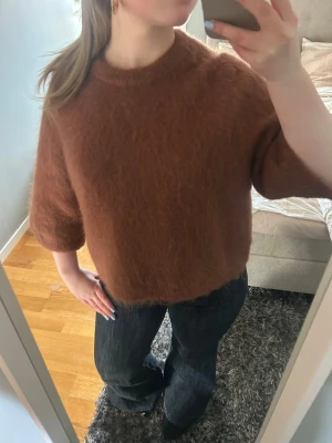 Brun fluffig stickad tröja - Säljer en brun, fluffig stickad tröja med rund hals och halvlånga ärmar. Tröjan har en boxy, lite croppad passform och är gjord i ett mjukt, lurvigt material som ger en mysig känsla. Perfekt för lager på lager och höstiga outfits. Kostar 900 i butik💗