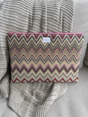 Zigzag-mönstrad datorväska från Emelo - Snygg datorväska från Emelo med färgglatt zigzag-mönster i beige, vinrött, olivgrönt och gult. Väskan har en rosa dragkedja och är tillverkad i ett kraftigt tygmaterial. Perfekt för dig som vill ha en unik och trendig look till din laptop. Passar laptop med maxmått: 33x24cm