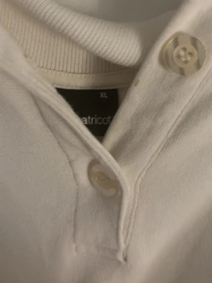 Vit långärmad tröja från Gina Tricot - Säljer en vit långärmad tröja från Gina Tricot i storlek XL. Tröjan har knappar vid halsen och ribbade muddar vid ärmslut och hals. Perfekt för en avslappnad och stilren look.