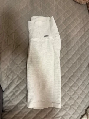 Vita shorts från Aimn - Säljer ett par vita  shorts från Aimn med strukturerat tyg och stretchig passform. De har en liten metallbricka med Aimn-logga framtill i midjan och är perfekta för träning eller chill dagar. Materialet känns sportigt och bekvämt. Passar perfekt nu till varmare dagar. Har aldrig använt byxorna innan.💕