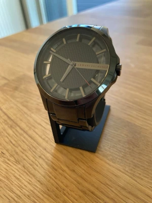 Armani Exchange AX2189 46mm Herrklocka - Säljer en Armani Herrklocka i unik design i gott skick. Finns enstaka märken och en skada i glaset. Fungerar utmärkt, original armband i rostfritt stål, vattentät, mineralglas, osv. Behöver bara nytt batteri.  Nypris: < 3000 SEK Mitt pris: 489 SEK  Skickas alltid snabbt och spårbart (ofta samma dag) se mina andra annonser också!  This Armani Exchange men's watch features a sleek textured black dial with cut-through index ring and a y-link