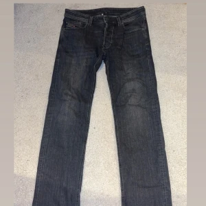 Diesel mörkgrå jeans 32/32  - Snygga Diesel jeans i mörkgrå tvätt med klassisk femficksdesign och raka ben. Perfekt passform och stilren look. Storlek 32/32.