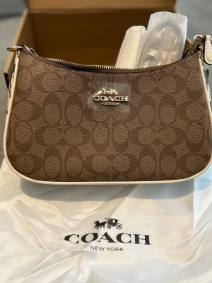 Coach Signature Mini Shoulder Bag  - Säljes nu en Coach Signature Mini Shoulder Bag i väldigt fint skick då den aldrig använts! Orginal karton samt orginal detaljer och tillbehör följes med! För mer frågor och info hör gärna av dig så svarar jag så gott jag kan💕