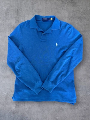 Långärmad Ralph Lauren Pike - Säljer min grymt snygga piké från Ralph Lauren i  en snygg ljusblå färg, perfekt nu inför sommarn. Två defekter på höger arm, inget som märks vid användning! Pris kan diskuteras 😁