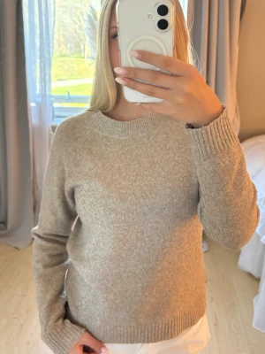 Beige stickad tröja med rund hals - Mysig beige stickad tröja med rund halsringning och långa ärmar. 
