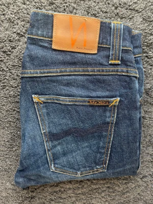 Premium Nudie Jeans | Grim Tim Dry Navy - Riktigt snygga nudie jeans i en fin tvätt.  🧵 Märke & Modell: Nudie Jeans - Grim Tim Org. Dry Navy 📏 Storlek & Passform: W32 L34. Sitter mer som en w31. Slim straight.  🧩 Material: 99% bomull / 1% elastan 📐 Mått: Midja: 38,5 cm Innerbens-söm: 79 cm Ytterbenslängd: 106 cm ✅ Skick: 9/10 – Väldigt väldigt fint skick, inte används mycket, men när dem används har det skapats snygga naturliga fades som ger en fin och bra karaktär på jeansen.  💰Nypris: 1500kr ‼️Skickas snabbt‼️