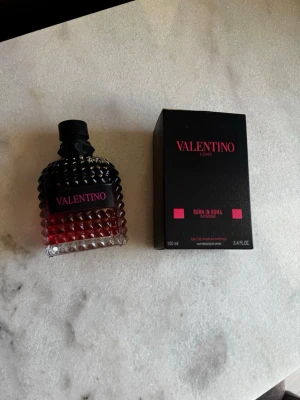 Valentino Born In Roma Intense 100ml - Lyxig valentino parfym, Uomo Born In Roma Intense. Flaskan är robust med nitar och har en snygg svart och röd design. Kommer i originalkartong. Perfekt för dig som gillar exklusiva dofter och vill sticka ut med en elegant flaska.