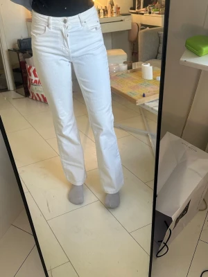 Vita raka jeans från Gina Tricot  - Säljer ett par vita jeans från Levis med rak passform och hög midja. Jeansen har klassiska fem fickor och är tillverkade i ett kraftigt denim-material. Perfekta för dig som vill ha en clean och stilren look.